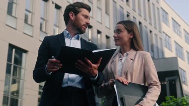 İki iş adamı ve kadın ellerinde klasör kağıtlarıyla şehirde iletişim kuruyor. Erkek patron, kadın yöneticiyle konuşuyor. İş projesi işadamı ve iş kadını hakkında konuşuyor.