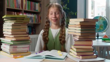 Kafkasyalı küçük kız okul çocuğu öğrenci öğrenci öğrenci öğrenci öğrenci öğrenci masasına oturur cep telefonu cihaz bağımlılığı ile iki yığın kitap okur ödevleri ihmal edip sınıfta online oyun oynarlar.