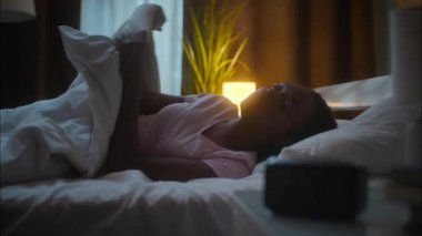 Uyuyan Afrikalı Amerikalı kadın kadın kadın battaniyeyi örterek yatağa uzanıyor. Uykusuzluktan uykusuzluktan uykusuzluktan uykusuzluk çekiyor.