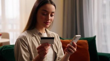 Kafkasyalı bir kadın cep telefonuyla internet üzerinden alışveriş yaparken mutlu bir şekilde banka kredi kartını öpüyor ve ev hanımı müşterilerine gülümsüyor. E-ticaret başarısı. Akıllı telefon uygulaması satın alarak yemek siparişi veriyor.