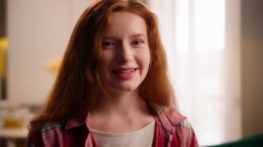 Mutlu, gülen, beyaz bir kız. Keyfi yerinde, mutlu bir kadın. Oturma odasında kameraya bakıyor, kaygısız bir kadın portresi izliyor.