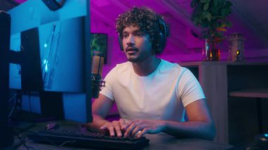 Amerikalı Arap asıllı Müslüman adam bilgisayar oyunu oynuyor bilgisayar oyunu oynayan adam sanal spor ağları erkek bilgisayar oyunu blogger streamer evde gece oyuncusuyla kulaklıklarda mikrofon konuşmalarında vlogger 'ı etkiliyor