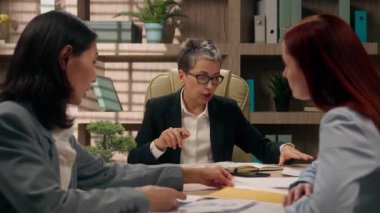Çeşitli iş kadınları, iş arkadaşları, ofis işkadınları, Kafkas lider koçları, grafiksel grafik grafikleri, kâr istatistikleri, çok ırklı işverenler, toplantı brifingi hakkında konuşuyorlar.