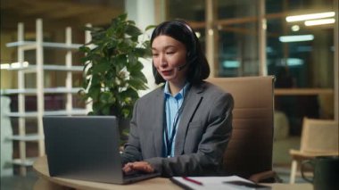 Neşeli Asyalı Koreli iş kadını ofis müdürü işkadını kadın bilgisayar daktilo eden müşteri danışmanı kulaklık operatörü Çinli kızla konuşuyor.