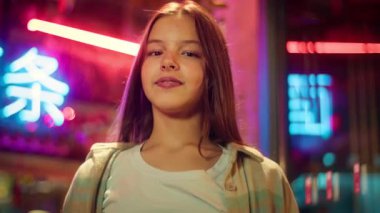 Neşeli beyaz Asyalı kız şehirde iki parmağını gösteriyor. Küçük mutlu genç gülümsemeli gözlüklü genç çocuk barış işareti takıyor. Neon dostu liseli kız.