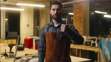 Mutlu beyaz adam ahşap ustası, atölyedeki zanaatkar, onaylı erkek sanatçı marangozu destekleyen, gülümseyen reaksiyon geliştirici tavsiyesi sunuyor.