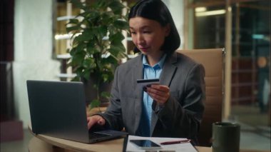 Asyalı Koreli Çinli kadın banka kartı tutuyor çevrimiçi sipariş dizüstü bilgisayarı kadın gülümseyen iş kadını iş kadını finansal uygulama ofisi alışverişi satın alıyor ev içi ödeme satın alıyor