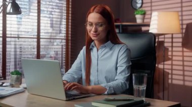 Ofiste dizüstü bilgisayarda çalışan beyaz iş kadını kameraya gülümseyen bir işaret gösteriyor. Kadın iş kadını. İnternette başarılı bir iş çıkarıyor.