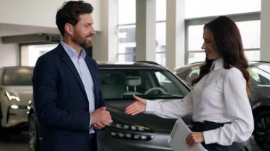 Kafkas erkek müşteri alıcısı kadın satış elemanı ile konuşuyor otomobil galerisinde el sıkışan iş adamı yeni araba tokalaşması satın alıyor satıcı kadın oto kiralama servisi alım-satımı sözleşmesi sonuçlandı