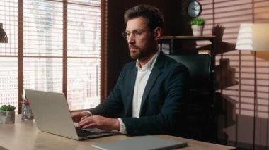 Beyaz, orta yaşlı iş adamı ofiste dizüstü bilgisayar yazarken kameraya gülümsüyor. Yetişkin iş adamı bilgisayarında çalışıyor. Danışman müşteriyle sohbet ediyor.