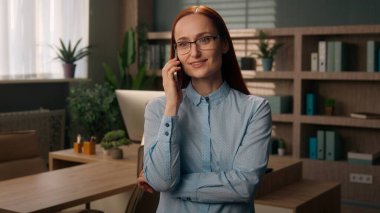 Gülümseyen kaygısız iş kadını cep telefonu konuşan Kafkasyalı kadın çalışan akıllı telefon konuşmaları iş kadını ofis müdürü iş yerinde cep telefonuyla konuşma