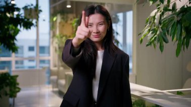 Asyalı iş kadını gülümseyen iş kadını başarılı bir şekilde iyi bir seçim gibi parmağınla işaret ederek mutlu bir hareket yap neşeli Çinli Çinli Çinli işveren yönetici portresi ofiste.