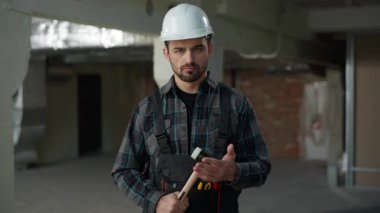Tamirci portre mühendisi kızgın adam inşaat alanında çekice vuruyor. Tadilat yaptırıyor. Üniformalı endüstri mimarı sinirden kuduruyor.