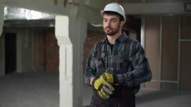 Eldiven giyen beyaz mühendis ustabaşı üniforması ile inşaat teknisyeni ustası tamirci, mimar, mühendislik mühendisliği güvenlik kuralları mimarisi üzerinde çalışmaya başla.