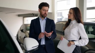 Otomobil galerisinde konuşan iki kişi, beyaz erkek müşteri müşteri işadamı, kadın satıcı otomobil tüccarı işadamıyla yeni lüks otomobil konuşmalarını seçiyor.