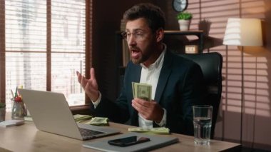 Duygusal, orta yaşlı, parası olan, video konferansından konuşan beyaz iş adamı. İş adamı, zengin erkek işverenin ofiste yaptığı konuşmada, tatmin olmamış maddi büyüme rakamlarını sayıyor.