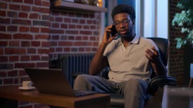Afro-Amerikalı iş adamı cep telefonu girişimcisini gece ofisinde fazla mesai yapan gülümseyen adam işvereni akıllı telefon dostu erkek danışman müşteriyle cep telefonu sohbeti yapıyor.