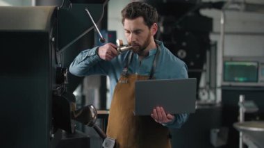 Kafkasyalı bir adam kavrulmuş kahve kumaşında çalışıyor. Kızartma makinesini teftiş ediyor. Kafein kokluyor, aroma kokluyor.