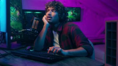 Latin Arap adam uykulu bir gece oyunu oynuyor bağımlı bilgisayar oyunu tükenmiş online oyun yorgun streamer stüdyo evi uykusuzluk çeken erkek internet uykusunda neon siber spor pc-sport akışı yapıyor