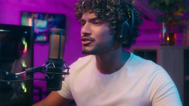 Arap Hintli Müslüman adam konuşan mikrofon blogcusu video oyunu oynuyor. Neşeli erkek oyuncu kazandı. Stüdyo siber spor sunucusu akışında zafer kazandı.