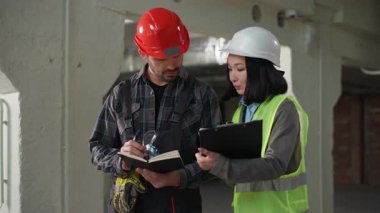 Çok uluslu odaklı mühendisler projesi, el sıkışma, el sıkışma, Asyalı kadın, beyaz şapkalı adam, pano inşaat sahası ortaklığı, takım çalışması mimarisi konularına dikkat çekiyor.