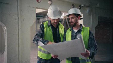 Bina planlamacısı arayan iki beyaz adam inşaat teknisyenleri ile el sıkışırken mimari taslak elektrikçiler endüstriyel iş mühendisleri teftişini kontrol ediyor.