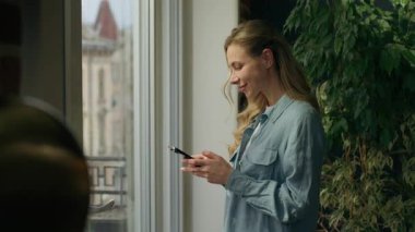 Mutlu kadın müşteri cep telefonu kullanıyor. Pencere daktilo kullanıyor. Beyaz tenli müşteri müşterisi. Kadın iş kadını, sohbet ediyor.