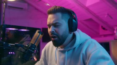 Uykucu Kafkasyalı erkek, erkek oyuncu, flamalı esneyen, tokat atan, uyanık kalmak için kulaklıkla oyun oynayan, neon odada mikrofonla oynayan, geceleri uykusuz kalan, oyun oynayan, yorgun oyuncu.