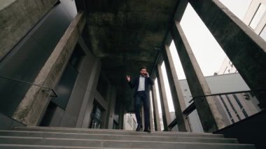 Stresli Kafkasyalı orta yaşlı iş adamı. Ofis toplantısına yetişmek için acele ediyor. Cep telefonuyla konuşuyor.