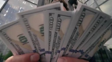 Orta yaşlı Kafkasyalı mutlu bir iş adamı dışarıda nakit para sayıyor kameraya bakıyor şehir işadamı iş yerindeki ofis binasının yakınındaki maaş artışına seviniyor iş adamı başarısı finans sayımı