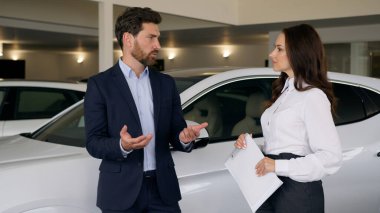 Kafkas erkek alıcı müşterisi otomobil kuaförü galerisinde kadın tüccar ile konuşuyor. Yeni lüks otomobil otomobili satın alan erkek araç taşıma test sürüşü test sürüşü kadın danışmanı seçimini tartışıyor.