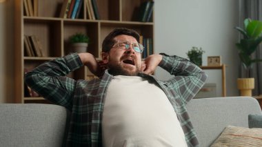 Gülümseyen, gevşeen, dinlenen, beyaz erkek, ev sahibi kanepede dinlenen, ev kredisi esneyen, uykulu, uykulu, uykulu, uykusuz, uykusuz, uykusuz, uykusuz, uykusuz bir adam.