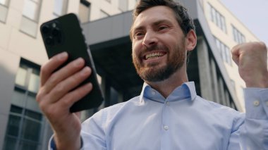 Başarılı işçi yetişkin Kafkasyalı işadamı 40 'lı yılların girişimci kazananı şehir inşaat işadamı erkek yönetici orta yaşlı başarılı cep telefonu akıllı telefonunu şehirde kutlayın