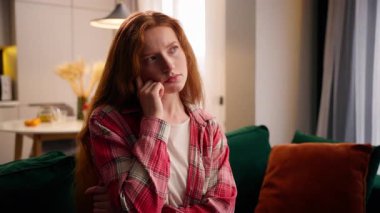 Evde düşünen düşünceli bir kadın. Çözüm planlama. Oturma odasında kanepede şaşkın şaşkın oturan bir kadın.
