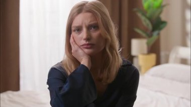 Depresyonda olan beyaz kadın, sabah yatak odasında kameraya bakıyor. Stresli kadın, üzgün kız, sağlık sorunları, iflas, üzgün kadın, kötü para sıkıntısı, depresyon portresi.