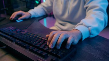 Beyaz adamın kollarını kapat erkek oyuncu dizüstü bilgisayar klavye yazma bağımlısı video oyunu bağımlısı gece vakti internet oyunu oynayan kapalı mekanda ışık saçan spor spikeri