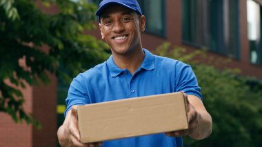 Postacının kaygısız erkek çalışanı postacı kurye adam gülümsüyor karton kutu standında çalışıyor şehir e-ticaret alışveriş postacılığı sokak kameralarına bakıyor.