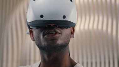 3D dünya oyunları oynayan Afrikalı Amerikalı erkek kontrolör VR başlık kullanıyor sanal artırılmış gerçeklik gözlükleri yüksek teknolojili internet teknolojisi fütürizm siber oyun arayüzü yenilik metaevren oynuyor