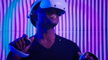 Heyecanlı Afrikalı Amerikalı erkek oyuncu erkek oyuncu oyun VR sanal gerçeklik gözlüğü, internet oyunu modern siber teknoloji, neon fütürizm kapalı mekanlarda fütürizm, yazılım AR tasarımcısı