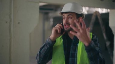 Sinirli Kafkasyalı müteahhit elinde cep telefonu ile inşaat ustabaşında uzaktan arama çatışması yapıyor öfkeli teknisyen inşaat endüstrisinde çalışan adamın tartışması erkek tartışmasını altüst ediyor