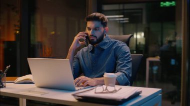 İşadamı Hintli adam gece yarısı çoklu iş adamı ofiste fazla mesai yapıyor cep telefonuyla konuşuyor bilgisayar ticareti, akıllı telefon görüşmeleri, gülümseyen müdür danışmanlık yapıyor.