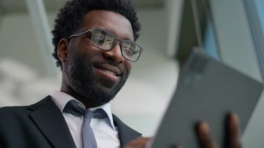 Afro-Amerikalı mutlu iş adamını kapat. Grafik dijital tablet bilgisayar aygıtı kullanarak gülümse. Kaygısız etnik erkek işadamı işçi.