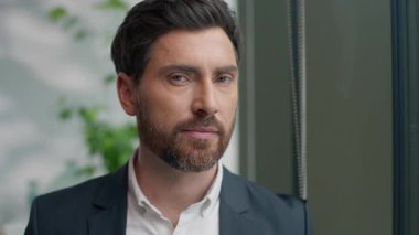 Kafkasyalı orta yaşlı iş adamının portresi ofiste pencereye bakıyor gülümseyen yetişkin iş adamı erkek profesyonel uzman yönetici şirket CEO 'su gamsız iş için gülümsüyor