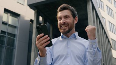 Başarılı işçi yetişkin Kafkasyalı işadamı 40 'lı yılların girişimci kazananı şehir inşaat işadamı erkek yönetici orta yaşlı başarılı cep telefonu akıllı telefonunu şehirde kutlayın