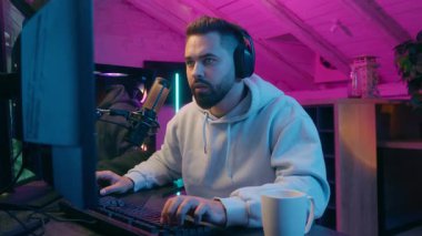 Uykucu Kafkasyalı erkek, erkek oyuncu, oyun kurucu esniyor, geceleri online oyun oynuyor, kahve içiyor, uyanık kalmak için düşük enerji uykusuzluk bağımlısı, neon odada oyun oynuyor, yorgun uykulu oyuncu yorgun.