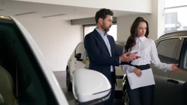 Düşünceli beyaz erkek müşteri alıcısı erkek, kadın satış elemanı ile yeni lüks otomobil pazarlamacısına danışmanlık yapmayı seçiyor. Otomobil galerisi işadamlarına danışmanlık yapıyor.