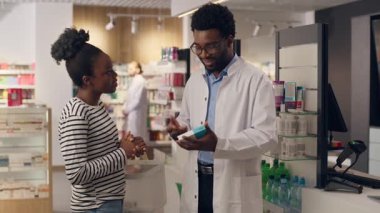 Eczane müşterisi ilaç tavsiyesi alıyor. Tıbbi danışmanlık, eczacılık, eczacılık, sağlık hizmetleri, reçeteli ilaç, eczanedeki Afrikalı Amerikalı erkek kadın, ilaç siparişinde müşteriye yardımcı oluyor.