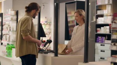 Eczacı kadın eczane kasasında ilaç satıyor. İlaç satın alan müşterilere yardım ediyor. Sağlık hizmetleri reçeteli eczane siparişi veriyor.