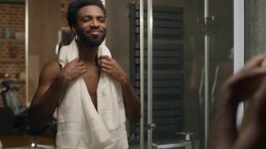 Banyoda sakallı, sakallı, aynadaki yansımaya bakan, sabah temizliği yapan, gülümseyen, nemlendirici, losyon jölesi, yumuşacık cilt kremi kullanan zenci bir adam.