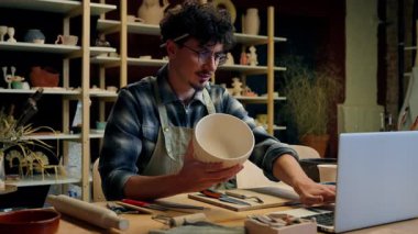 Potter Kafkas erkek heykeltıraş küçük işletme sahibi seramik çevrimiçi dizüstü bilgisayar alışverişi erkek zanaatkar tasarımcı el yapımı çanak çömlek taşları satan sanat eseri atölyesinde e-ticaret